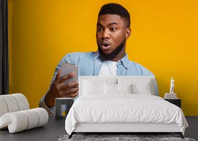 Surprised african man looking at smartphone screen with mouth opened Wall mural