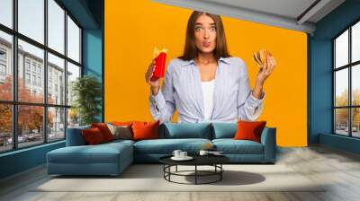 Surprised Woman Eating Burger And French Fries, Studio Shot Wall mural