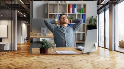 Taking break. Middle aged man relaxing on chair sitting at workplace and resting in office, leaning back Wall mural