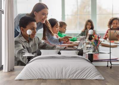 Teacher Teaching Diverse School Kids Using Laptop In Classroom Wall mural