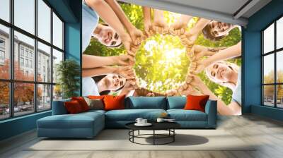 Team of happy volunteers fist bump together in park Wall mural