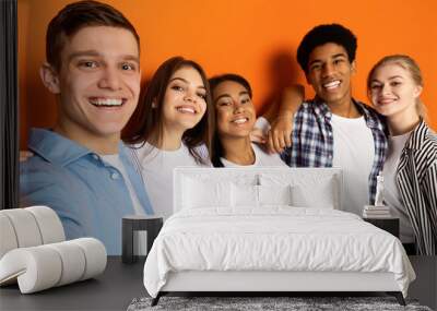 Teen friends making selfie and having fun, orange background Wall mural