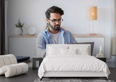 Telecommuting. Eastern Man Using Laptop Computer, Sitting At Desk In Home Office Wall mural