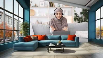 Teleconference. Smiling muslim woman having video call on laptop at home Wall mural