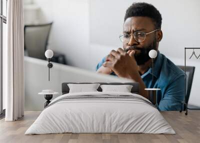 Thoughtful black man in eyeglasses stack with hard task, looking at computer screen, thinking of problem solution Wall mural