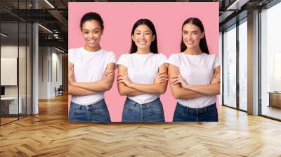 Three Multiethnic Women Posing Crossing Hands Over Pink Background, Studio Wall mural