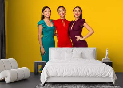 Three Multiracial Models In Dresses Standing Over Yellow Studio Background Wall mural