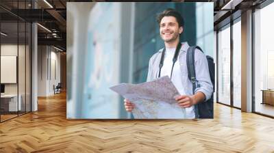 Tourist man looking for route on map at airport Wall mural