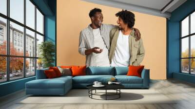 Two Cheerful Black Male Friends Embracing And Laughing On Beige Background Wall mural