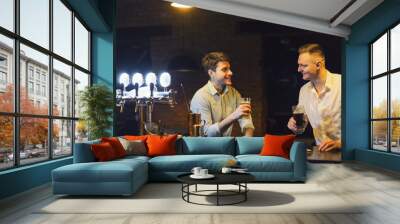 Two happy young men talking and drinking beer at bar Wall mural