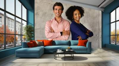 Two successful multicultural businesspeople standing back to back, arms crossed Wall mural