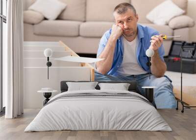 Unhappy Man Assembling Furniture Having Trouble Installing Cabinet At Home Wall mural