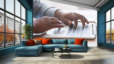 Unrecognizable african american man typing on laptop keyboard in office Wall mural