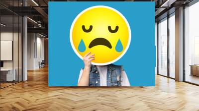 Unrecognizable man hiding his face behind crying sad emoticon emoji Wall mural