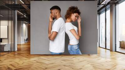 Upset couple standing back to back on gray background Wall mural