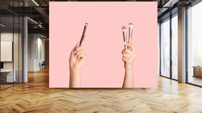 Various makeup brushes in female hands on pink background, closeup. Collage. Panorama Wall mural