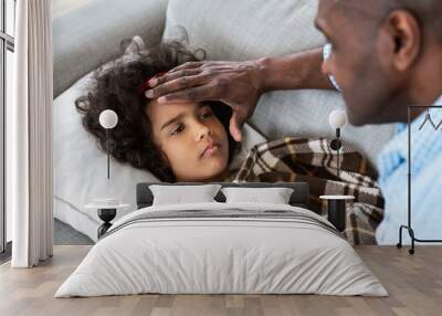 Virus outbreak. Senior African American man touching his granddaughter's forehead, checking fever at home Wall mural