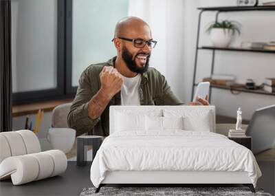 Win. Portrait of excited mature man celebrating success shaking clenched fist using cellphone, reading great news Wall mural