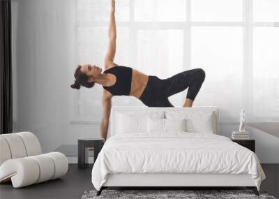 Woman doing side plank exercise at modern studio Wall mural