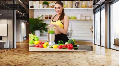 Woman Making Healthy Juice With Machine In Kitchen Wall mural