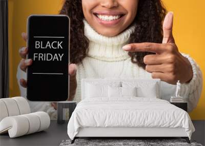 Woman showing cell phone with black friday text on screen Wall mural