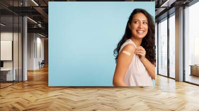 Woman Showing Vaccinated Arm With Bandage After Injection, Blue Background Wall mural