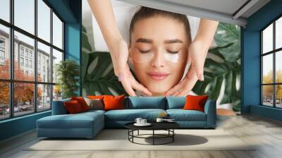 Woman with eye patches having face massage Wall mural