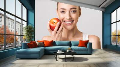 Woman With Perfect Smile Holding Apple Posing On Gray Background Wall mural