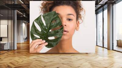 Woman with tropical leaf covering half of face Wall mural