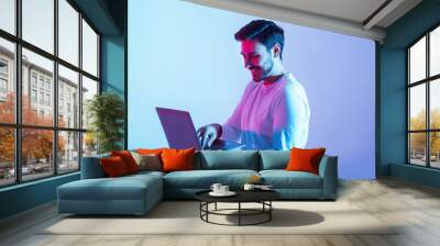 Work and play online. Happy guy holding laptop and typing Wall mural