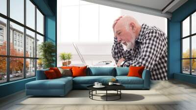 Worried senior man using laptop at home Wall mural