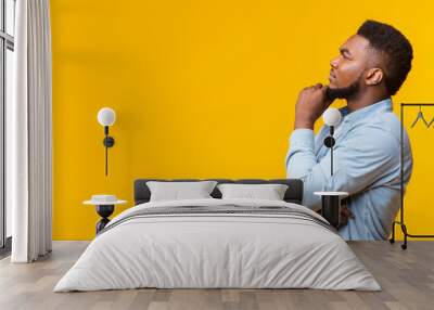 Young african american guy thinking about something over yellow background Wall mural