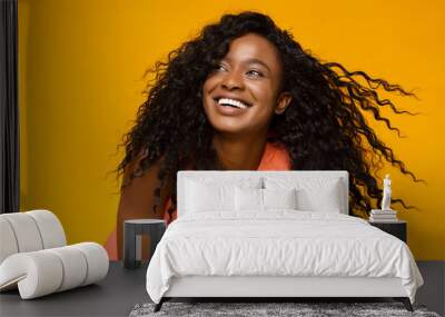 Young african woman laughing on yellow background Wall mural