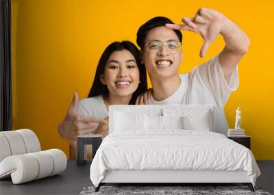 Young asian couple showing frame sign with fingers Wall mural