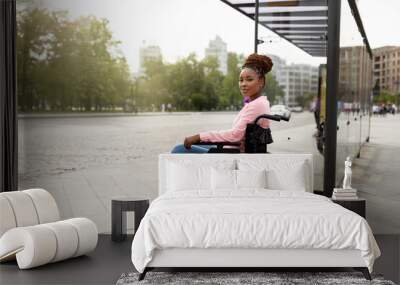 Young black handicapped woman in wheelchair cannot board vehicle suitable for impaired persons, waiting on bus stop Wall mural