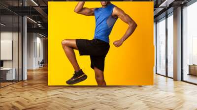 Young black sportsman walks highly lifting his knees Wall mural