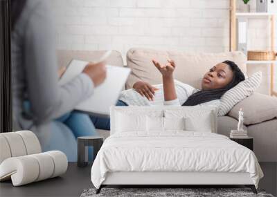 Young black woman lying on couch, sharing problems at counselor's office Wall mural