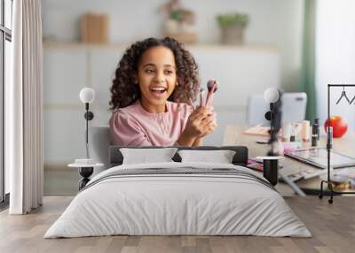 Young blogger. Happy teen girl showing her brushes and doing makeup, filming video for her channel Wall mural