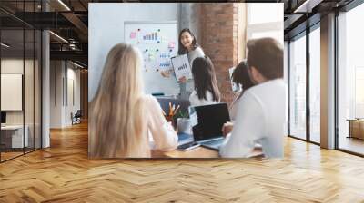 Young business team listening to girl with marketing report Wall mural