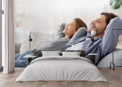 Young chilling couple enjoying day off at home Wall mural