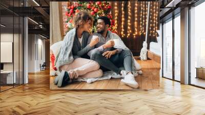 Young couple drinking coffee at Christmas tree Wall mural