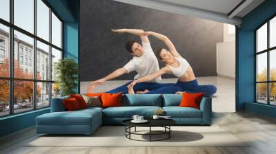 Young couple practicing yoga together in gym Wall mural