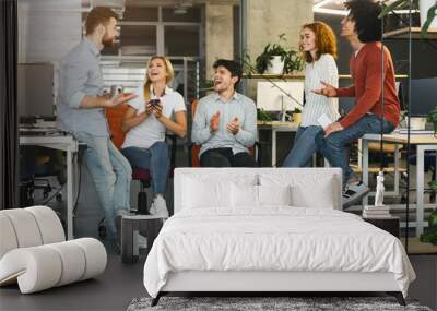 Young coworkers having pleasant talk in office Wall mural