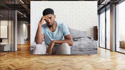 Young depressed black man sitting on bed Wall mural