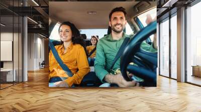 Young european parents and daughter riding new car and smiling, enjoying road trip together Wall mural