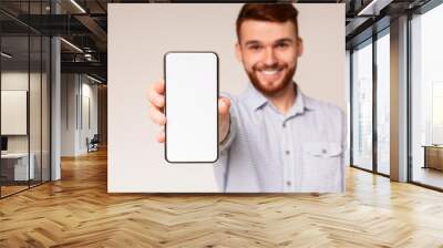 Young guy showing his phone with blank space on camera Wall mural