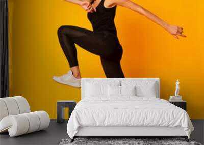 Young Lady Jumping During Workout On Yellow Background, Side View Wall mural