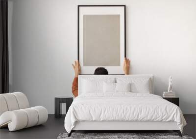 Young man hanging picture frame on the wall Wall mural