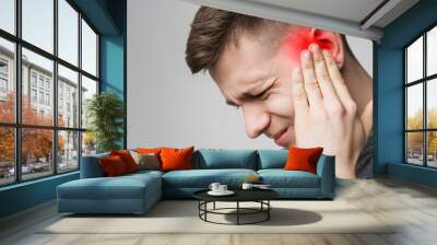 Young man has sore ear, suffering from otitis Wall mural