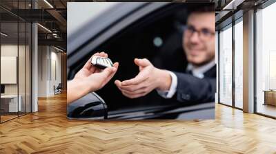 Young man taking auto key, sitting on driver's seat Wall mural